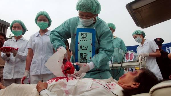 Los practicantes de Falun Dafa simulan la sustracción de órganos en un campo de trabajo chino para protestar por sospecha de abuso y asesinato de China. (AP)