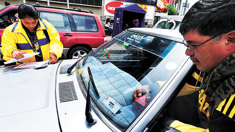 Un funcionario de una aseguradora coloca el sticker del SOAT en un auto de transporte público