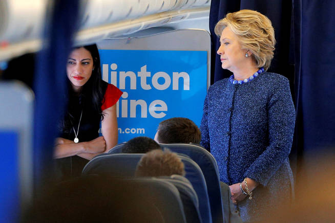 Hillary Clinton habla con su equipo, incluida Huma Abedin, durante un trayecto de campaña en avión. (Reuters)