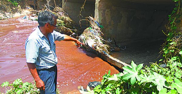 El vecino Raymundo Ríos muestra cómo el agua pasa por debajo de la alcantarilla, socavando la estructura, que se puede venir abajo