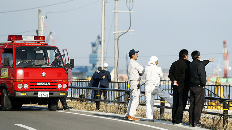 Bomberos y ciudadanos miran hacia el mar después de declararse una alerta de tsunami en la prefectura de Fukushima (Japón).