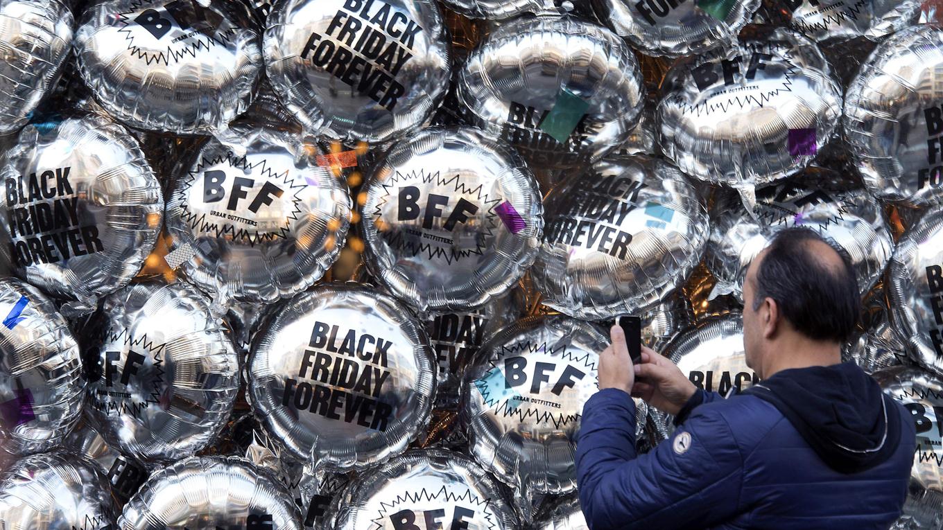 Un hombre usa un teléfono móvil para fotografiar globos temáticos de "Black Friday" leyendo "Black Friday Forever" y "BFF" formando una vitrina de una tienda minorista en Oxford Street, Londres. Foto: AFP / Justin Tallis