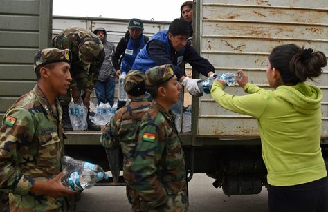 Una vecina afectada por la crisis en La Paz recibe agua embotellada que comenzó a distribuir el Gobierno.