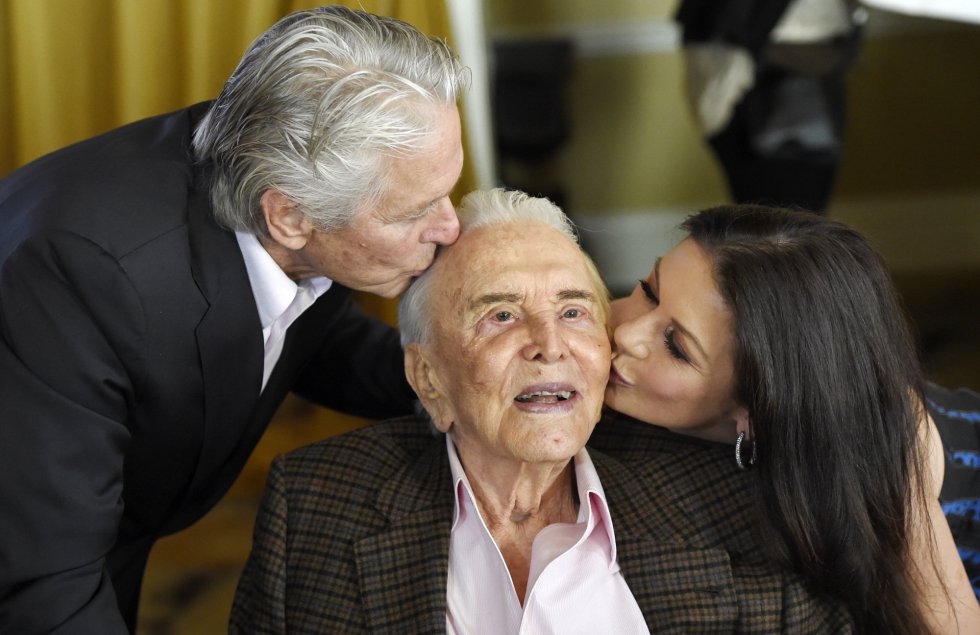 El actor Kirk Douglas, besado por su hijo Michael Dougas y por la esposa de este, Catherine Zeta-Jones, en la fiesta por sus cien años en el hotel Beverly Hills, de California, ayer viernes.
