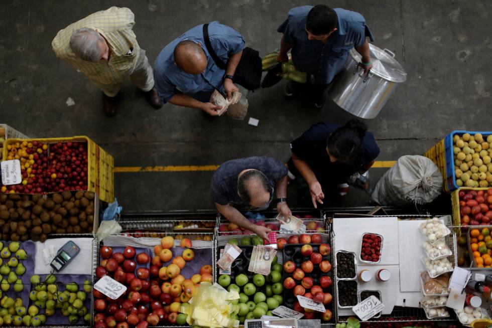 Los clientes cuentan bolívares en un mercado de Caracas.