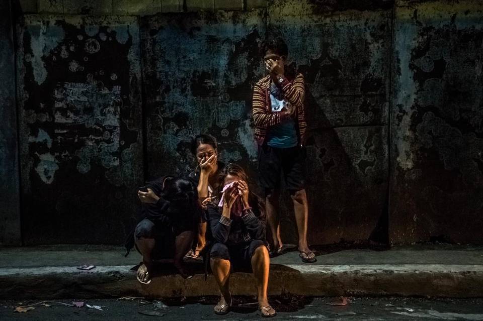 Familiares de las víctimas lloran en la calle donde yacen los cuerpos de Frederick Mafe y Arjay Lumbago en Manila, Filipinas, el 3 de octubre.