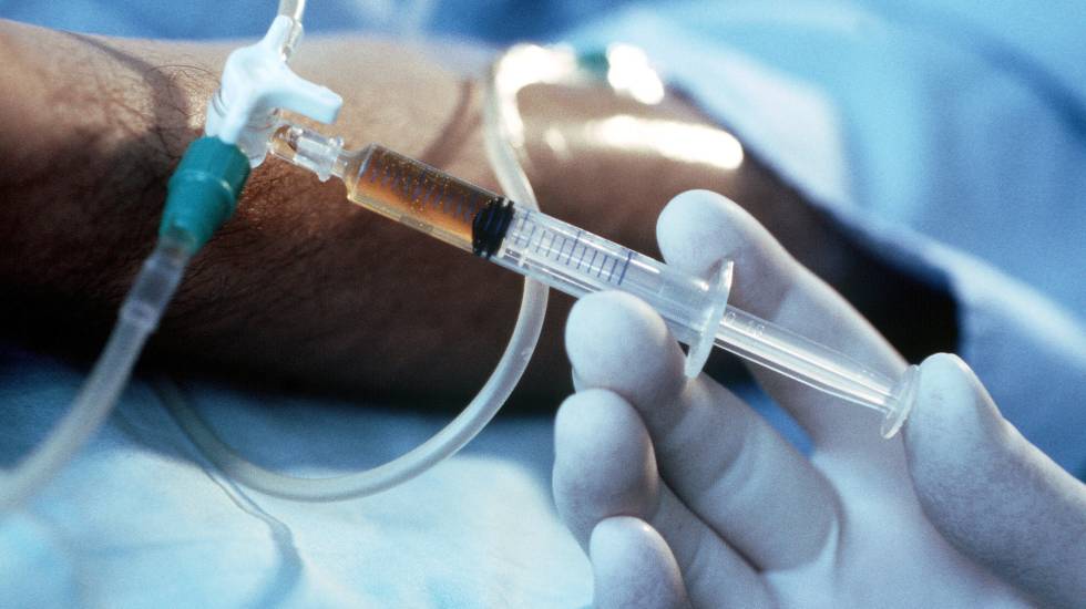 En un caso de eutanasia, una mano con guantes quirúrgicos inyecta un líquido en un vial.