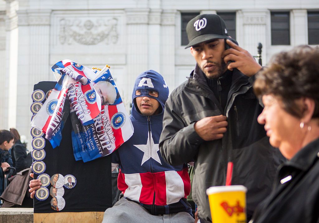 Un hombre vestido como Capitán América vende botones y banderas de Trump para su llegada a la Casa Blanca. (Crédito: Jessica Kourkounis/Getty Images)