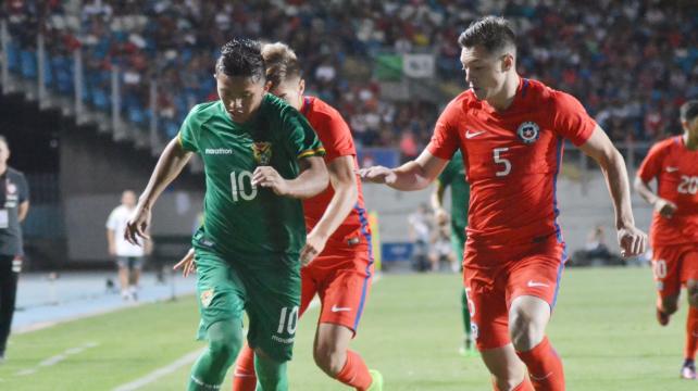 El boliviano Jhon García (10) trata de escapar de la marca de un defensor de Chile. Foto: FBF %image_alt%