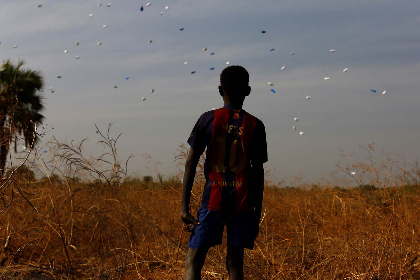 A boy watches sacks of food drop to the ground during a United Nations World Food Programme (WFP) airdrop close to Rubkuai village in Unity State, northern South Sudan, February 18, 2017. Picture taken February 18, 2017. REUTERS/Siegfried Modola