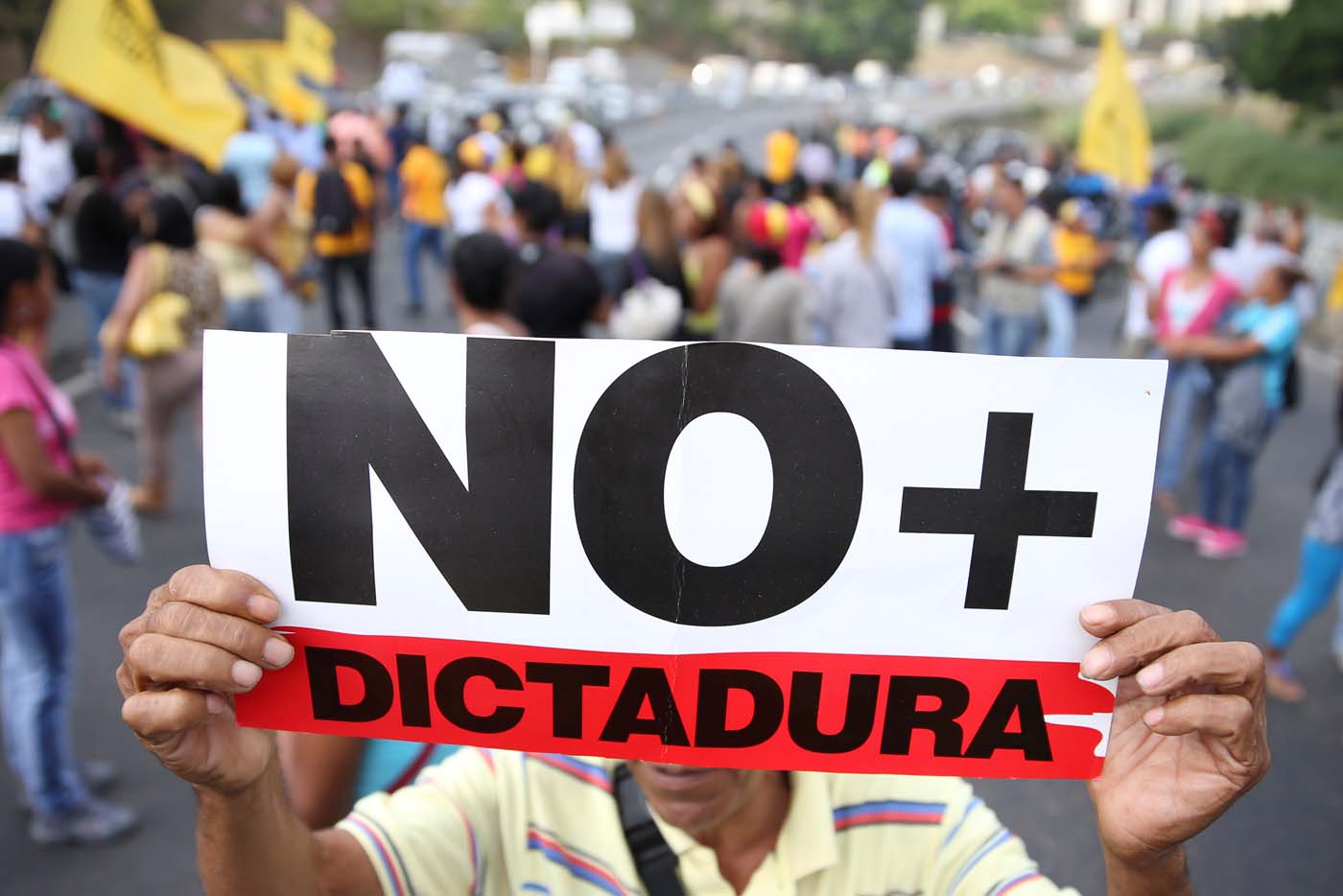 Opposition supporters holding a placard that reads, "No more dictatorship" shout slogans as they block a highway during a protest against Venezuelan President Nicolas Maduro