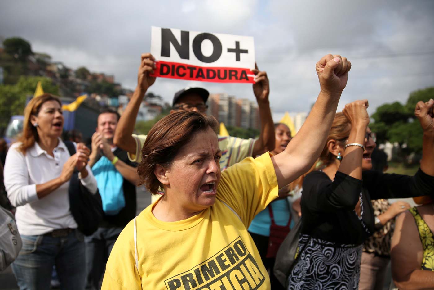 Opposition supporters holding a placard that reads, "No more dictatorship" shout slogans as they block a highway during a protest against Venezuelan President Nicolas Maduro