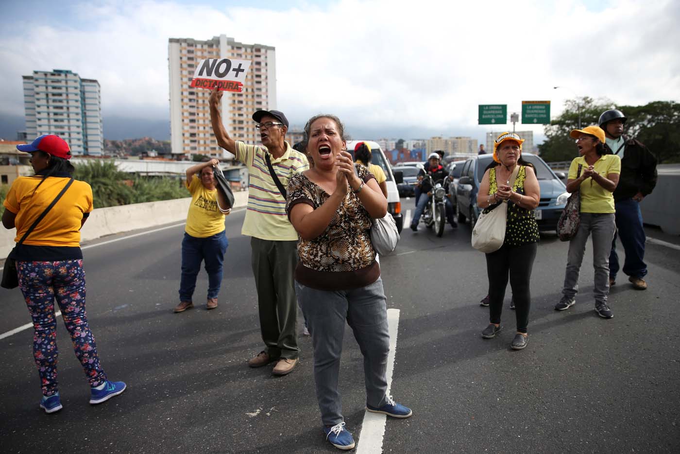 Opposition supporters holding a placard that reads, "No more dictatorship" shout slogans as they block a highway during a protest against Venezuelan President Nicolas Maduro
