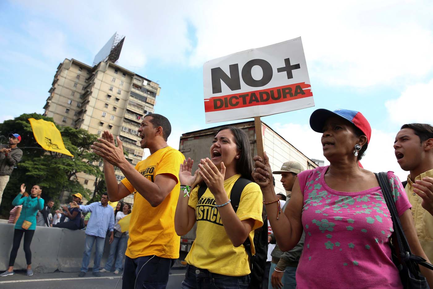 Opposition supporters holding a placard that reads, "No more dictatorship" shout slogans as they block a highway during a protest against Venezuelan President Nicolas Maduro