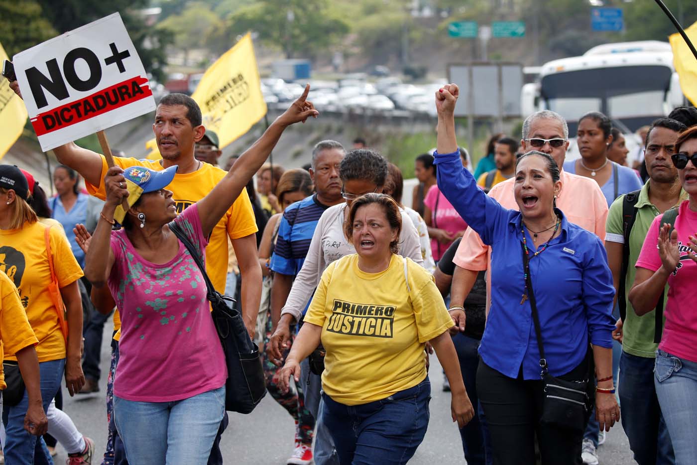 Opposition supporters holding a placard that reads, "No more dictatorship" shout slogans as they block a highway during a protest against Venezuelan President Nicolas Maduro