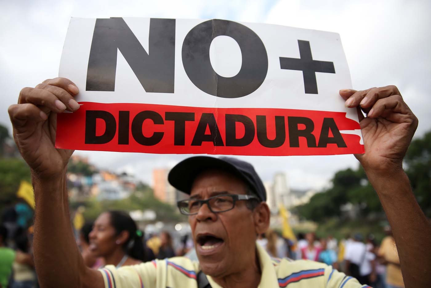 An opposition supporter holding a placard that reads, "No more dictatorship" shouts slogans as he blocks a highway during a protest against Venezuelan President Nicolas Maduro