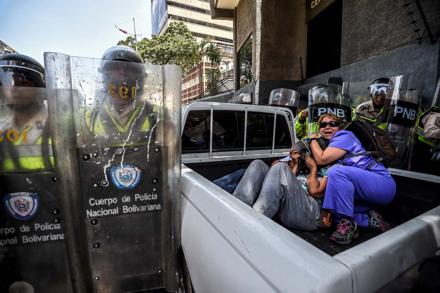 People protect themselves during clashes between opposition activists and riot police agents during a demonstration against Nicolas Maduro