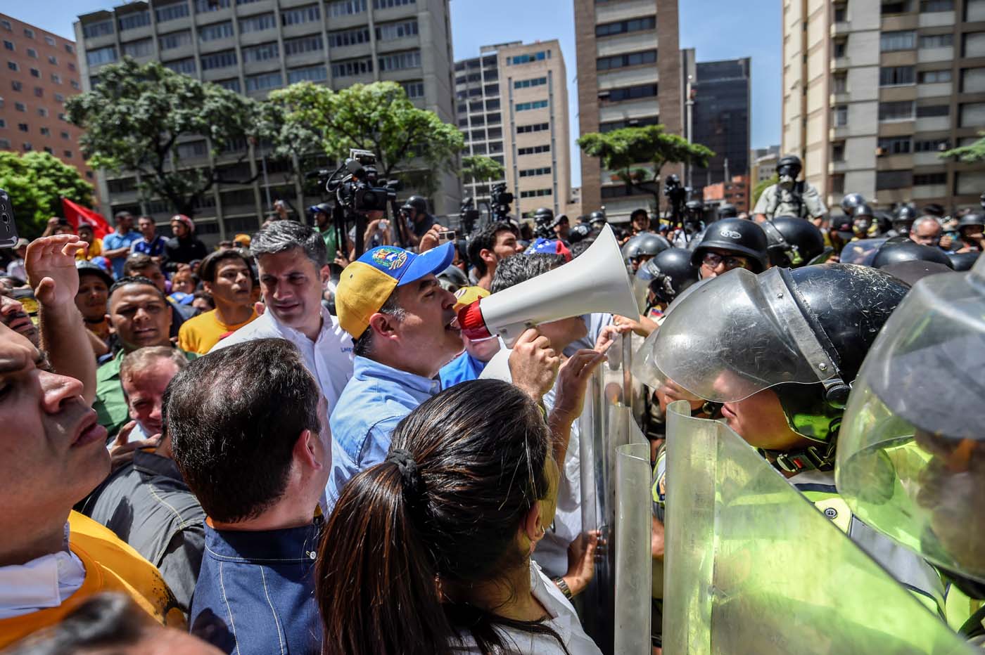 The President of the National Assembly Julio Borges using a megaphone addresses riot police agents during a protest against Nicolas Maduro
