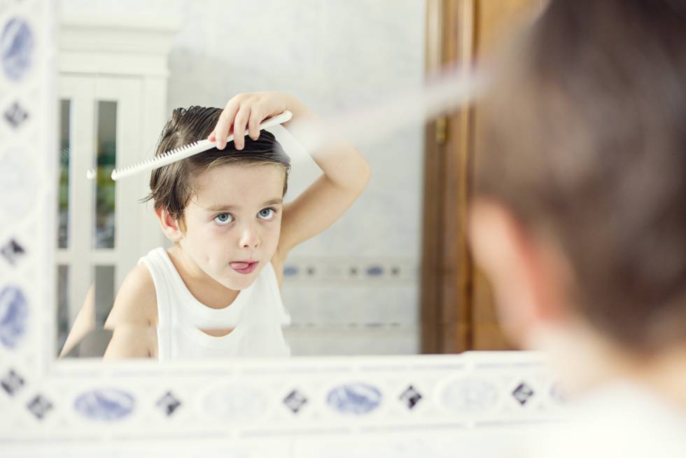 Un niño se repeina frente al espejo. 