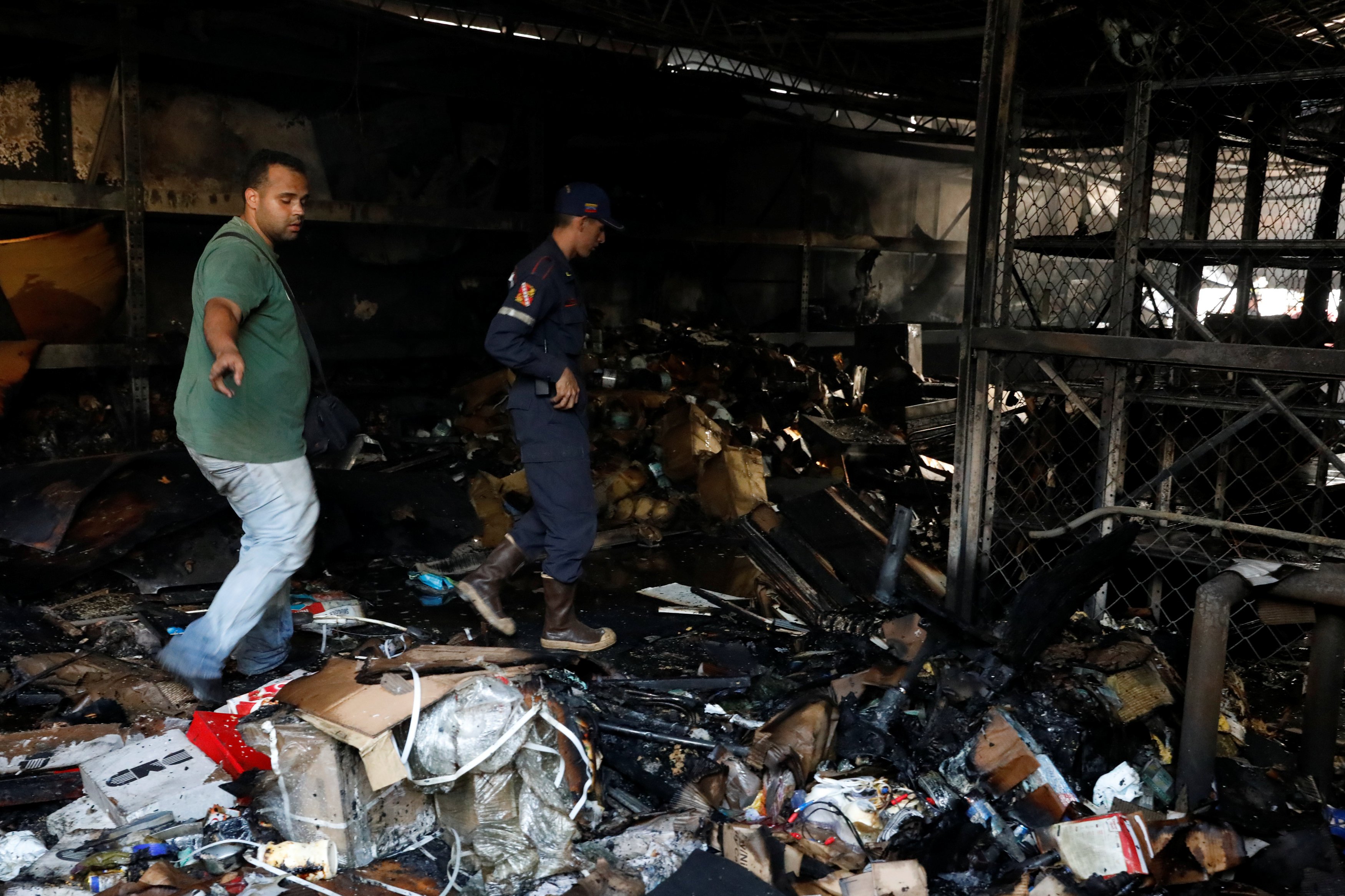 A fireman and another man walk past burned debris in a warehouse in the building where the offices of Venezuelan opposition leader and Governor of Miranda state Henrique Capriles are located, in Caracas, Venezuela April 8, 2017. REUTERS/Carlos Garcia Rawlins