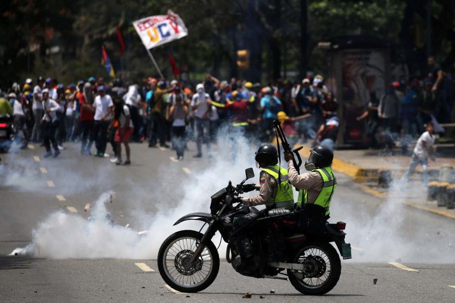 Demonstrators clash with riot police at a rally against Venezuela