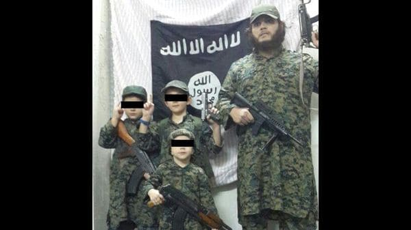 Sharrouf junto con sus hijos posando frente a una bandera del Estado Islámico