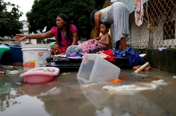 Una madre y su niño lavan ropa a las orillas del río en Manaos (Reuters)