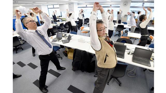Los empleados de una empresa de tecnología mientras hacen ejercicios en sus oficina, después de la hora del almuerzo en Tokio.
