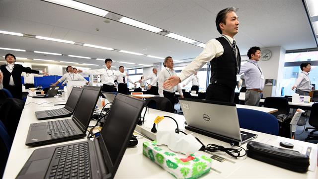 Los empleados de una empresa de tecnología mientras hacen ejercicios en sus oficina, después de la hora del almuerzo en Tokio.