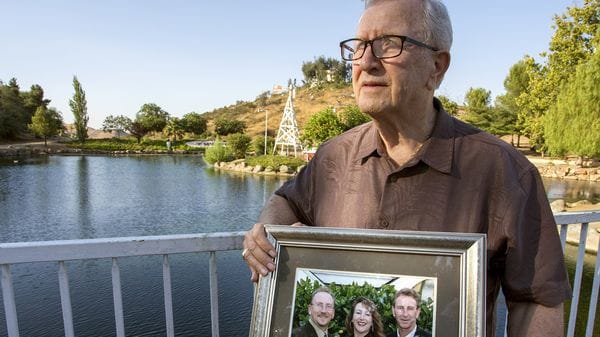 Frank Kerrigan y una foto de sus tres hijos, al vivir la confusa experiencia de enterrar a alguien que no era quien creía (AP)