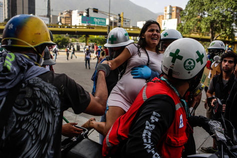Personal médico auxilia a una persona afectada por los gases lacrimógenos durante el "trancazo" en Caracas. Foto: EFE