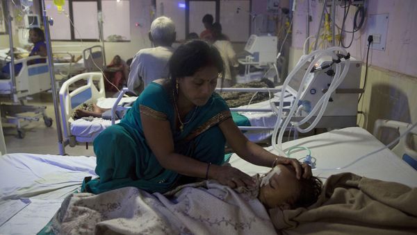 Una mujer atiende a un infante en el hospital. Más de 30 infantes murieron en tres días (AP)