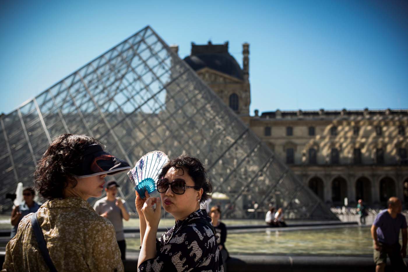(FILES) This file photo taken on August 25, 2016 shows people standing at the Louvre museum in Paris as temperatures soar across the country. After a decline in 2016 due to the terror attacks in Paris and Nice, tourism in Paris and Ile de France is in much better shape in the first half of 2017, with 1,5 million tourists and 3,3 million overnight stays more than a year ago. / AFP PHOTO / LIONEL BONAVENTURE