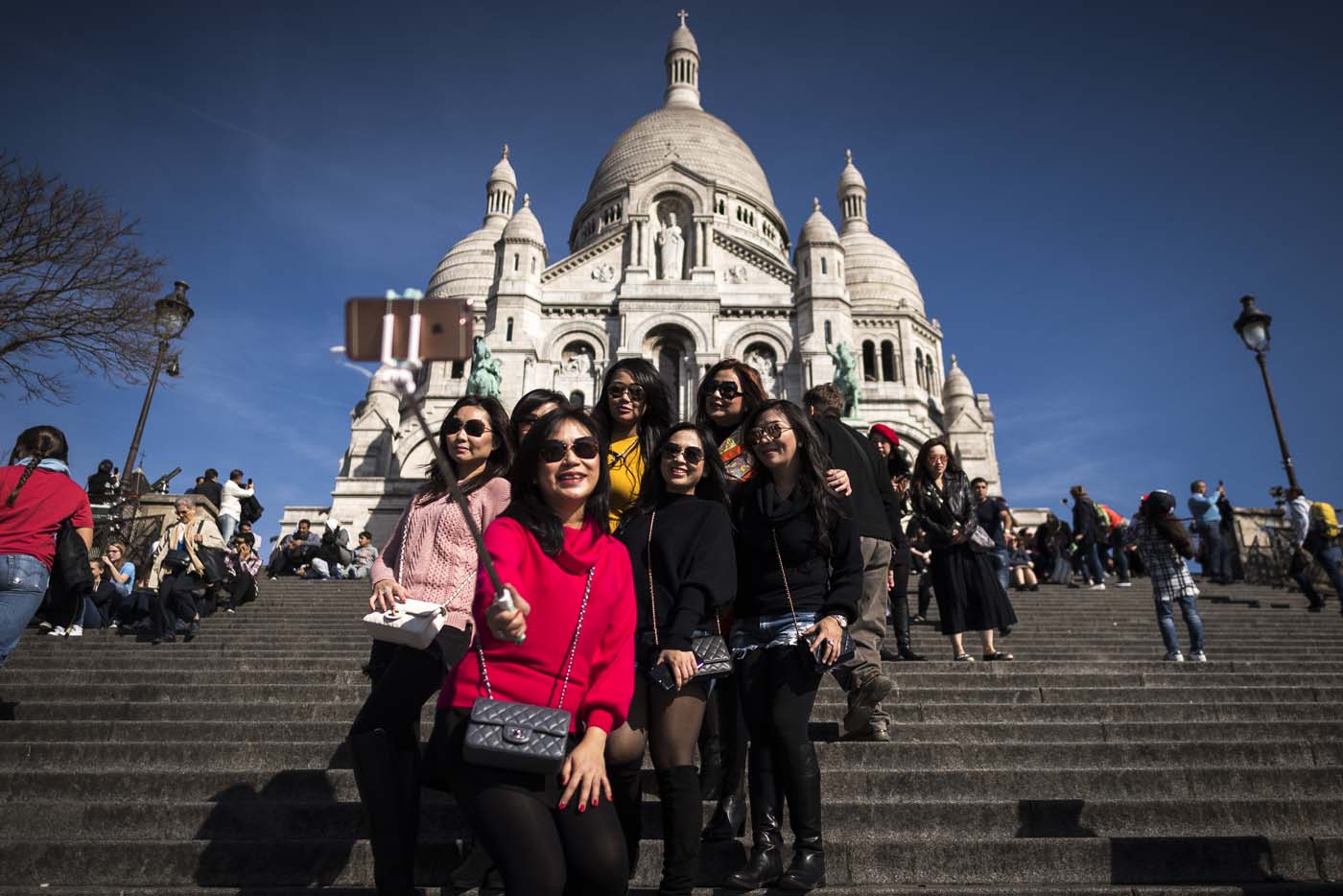 (FILES) This file photo taken on March 30, 2017 shows tourists taking selfie pictures in front of the Sacre Coeur basilica ontop of the Paris landmark district of Montmartre in Paris. After a decline in 2016 due to the terror attacks in Paris and Nice, tourism in Paris and Ile de France is in much better shape in the first half of 2017, with 1,5 million tourists and 3,3 million overnight stays more than a year ago. / AFP PHOTO / Lionel BONAVENTURE
