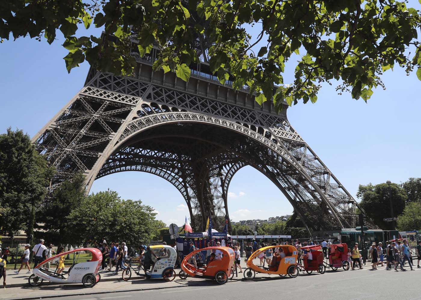(FILES) This file photo taken on July 07, 2017 shows Pedicab drivers waiting for clients near the Eiffel Tower in Paris. After a decline in 2016 due to the terror attacks in Paris and Nice, tourism in Paris and Ile de France is in much better shape in the first half of 2017, with 1,5 million tourists and 3,3 million overnight stays more than a year ago. / AFP PHOTO / JACQUES DEMARTHON