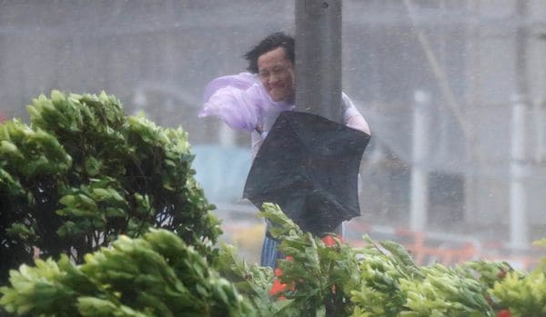 Un hombre se sostiene de un poste ante las ráfagas de viento en Hong Kong (Reuters)