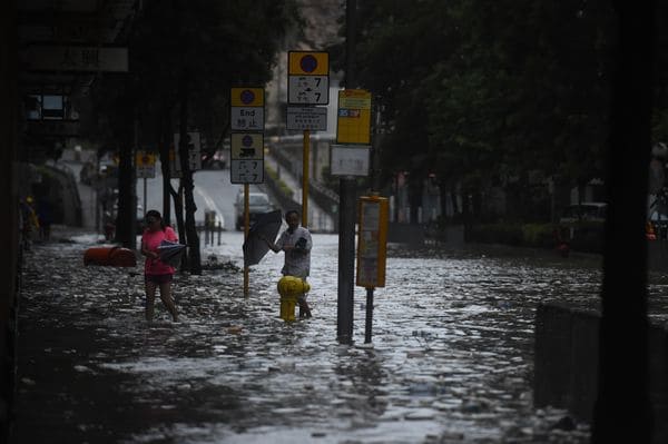 Residentes caminan por las calles inundadas en Heng Fa Chuen, Hong Kong (AFP)