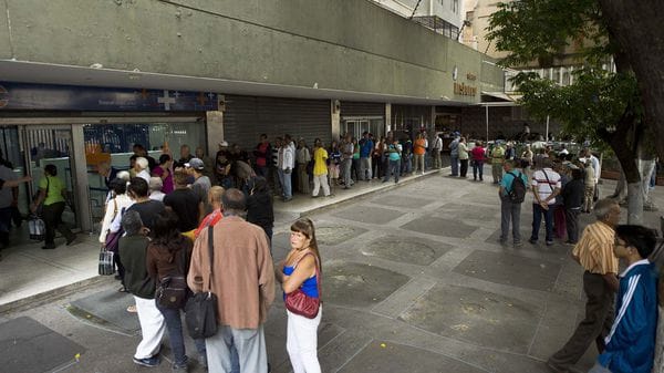 Decenas de personas hacen fila en un banco de Caracas para sacar de dinero. (AFP)