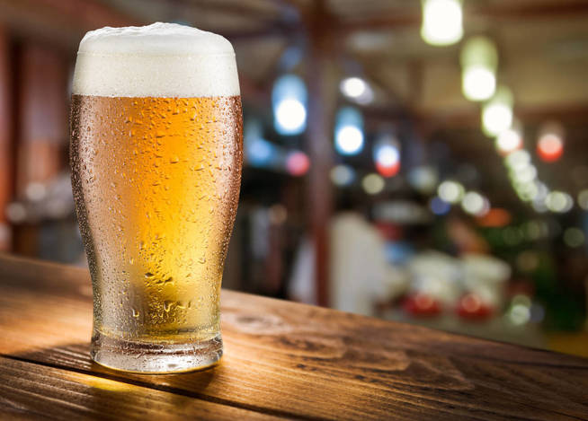 Glass of light beer on the glass bar counter.