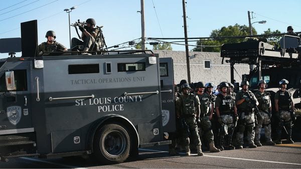 Chalecos, fusiles de asalto y francotirador y un vehículo blindado durante las protestas en Ferguson en 2015 que llevaron al presidente Obama a limitar ese equipo (AFP)