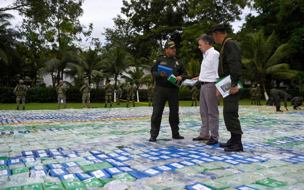 El presidente de Colombia, Juan Manuel Santos, y dos agentes sobre las más de 12 toneladas de cocaína incautada. rn rn rn 