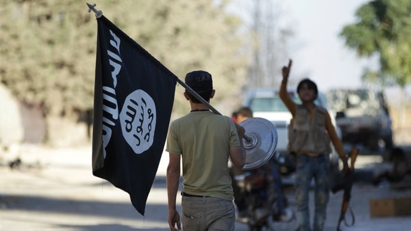 Un rebelde lleva como trofeo una bandera del Estado Islámico (Reuters)