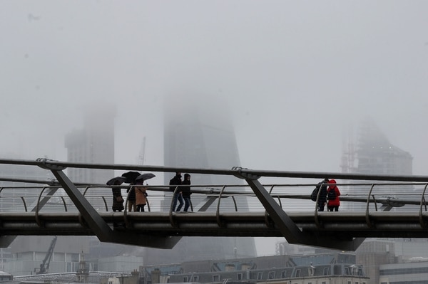 Transeúntes bajo la nieve en el Millennium Bridge de Londres (AFP)
