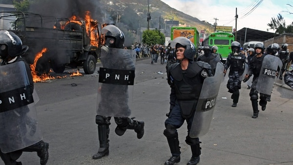 Oficiales se movilizan mientras arde un vehículo policial, en Tegucigalpa (AFP)
