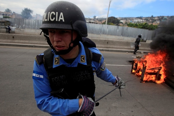 Un policía retira un objeto en llamas de una barricada opositora (Reuters)