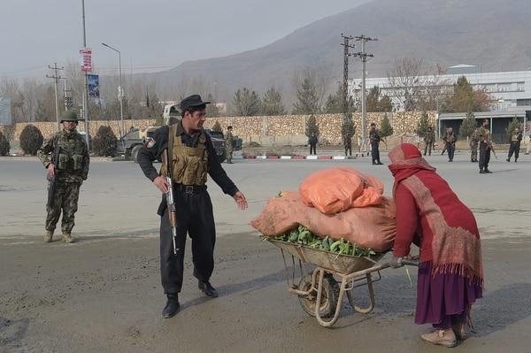 Un miembro de las fuerzas de seguridad impide que una mujer se acerque al lugar del ataque (AFP)