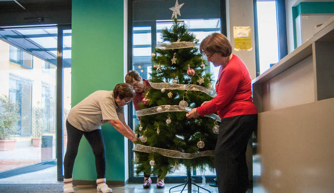 Dos residentes de Trabensol decoran un árbol de Navidad. (Carmen Castellón)