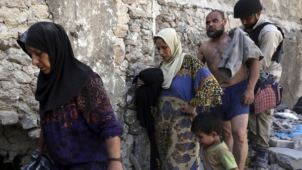 Un grupo de civiles abanadona su escondite tras el fin de la batalla. El hombre está en ropa interior para demostrar que no es un combatiente del ISIS camuflado (EFE)