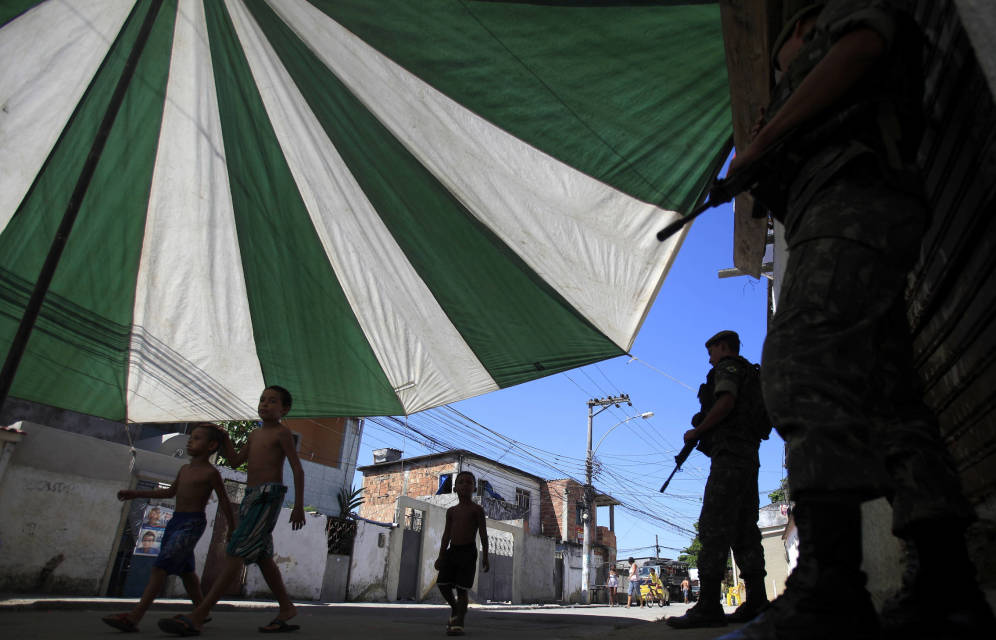 Foto: Unos niños pasan ante soldados brasileños que patrullan por la favela Muquico, en Río de Janeiro. (Reuters)