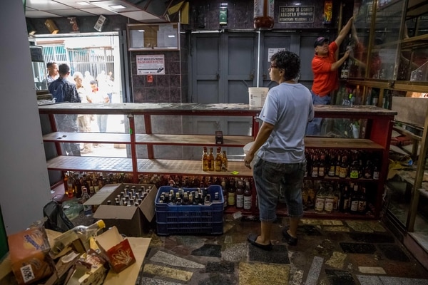Un trabajador de una licorera que fue saqueada en horas de la madrugada en el sector La Vega saca productos del local comercial en Caracas (Venezuela). (EFE/Miguel Gutiérrez)